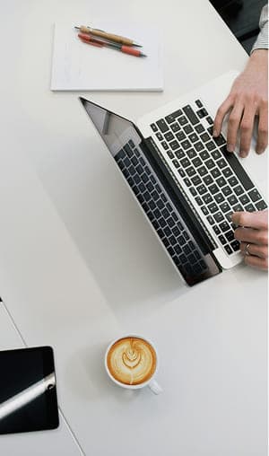 清潔感のあるデスクでノートパソコンとコーヒーとともに仕事をする様子